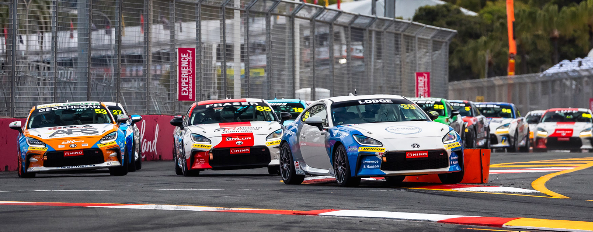 A fleet of GR86 racing vehicles make laps of the track at the GR Cup on the Gold Coast, the track sitting amongst the high rise coastal apartments.