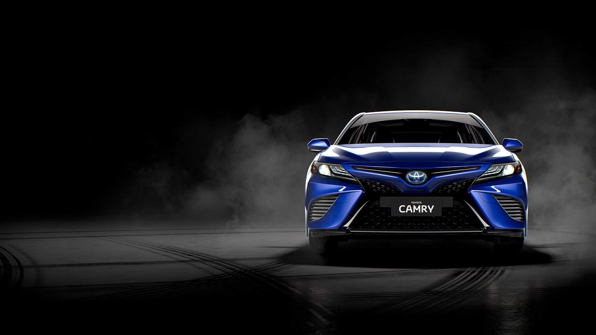 A dark blue Toyota Camry Hybrid Sedan, dramatically lit in a studio, surrounded by a light mist.