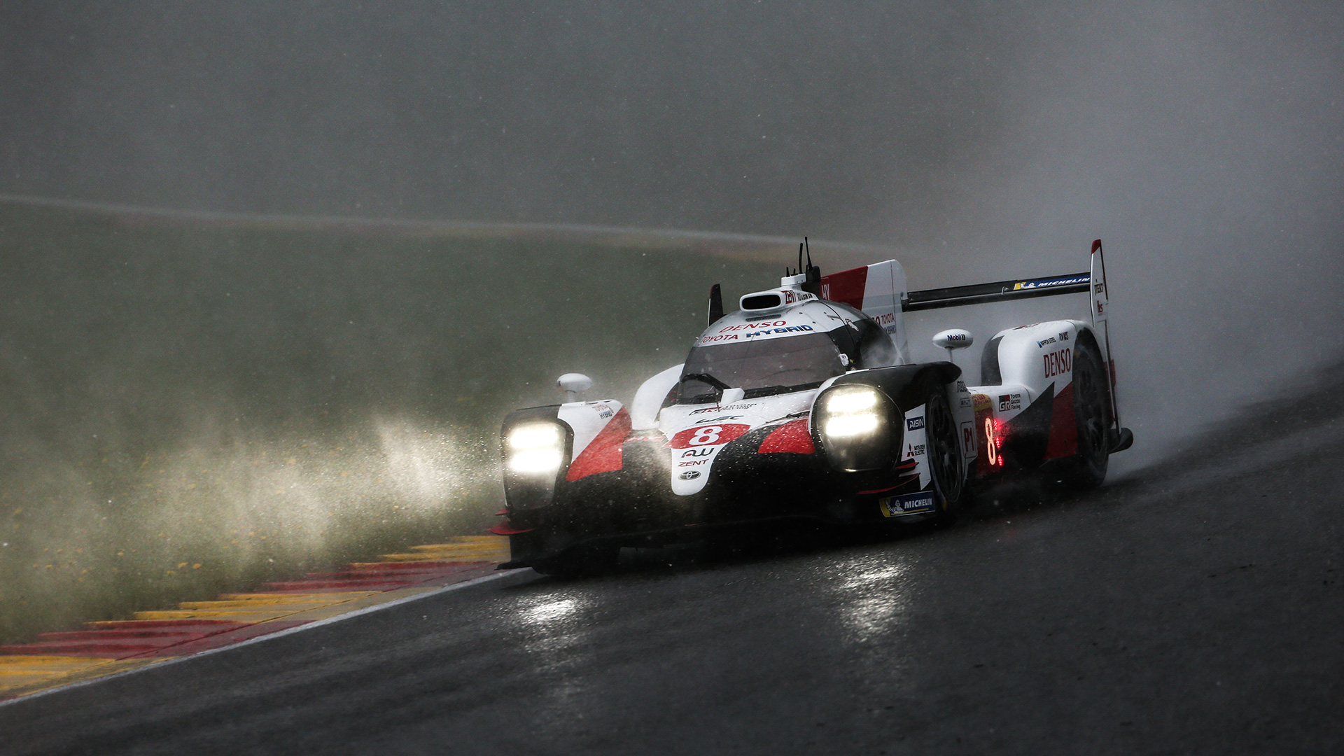 A Toyota TS050 Hybrid Le Mans Prototype kicking up water on the rain-soaked Circuit de la Sarthe race track at 24 Hours of Le Mans.