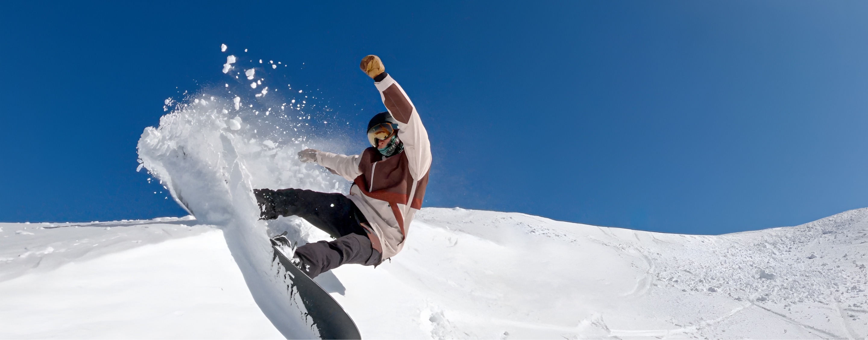 Australian Paralympian snowboarder Ben Tudhope, kicking up snow mid-air, while snowboarding down a mountain.