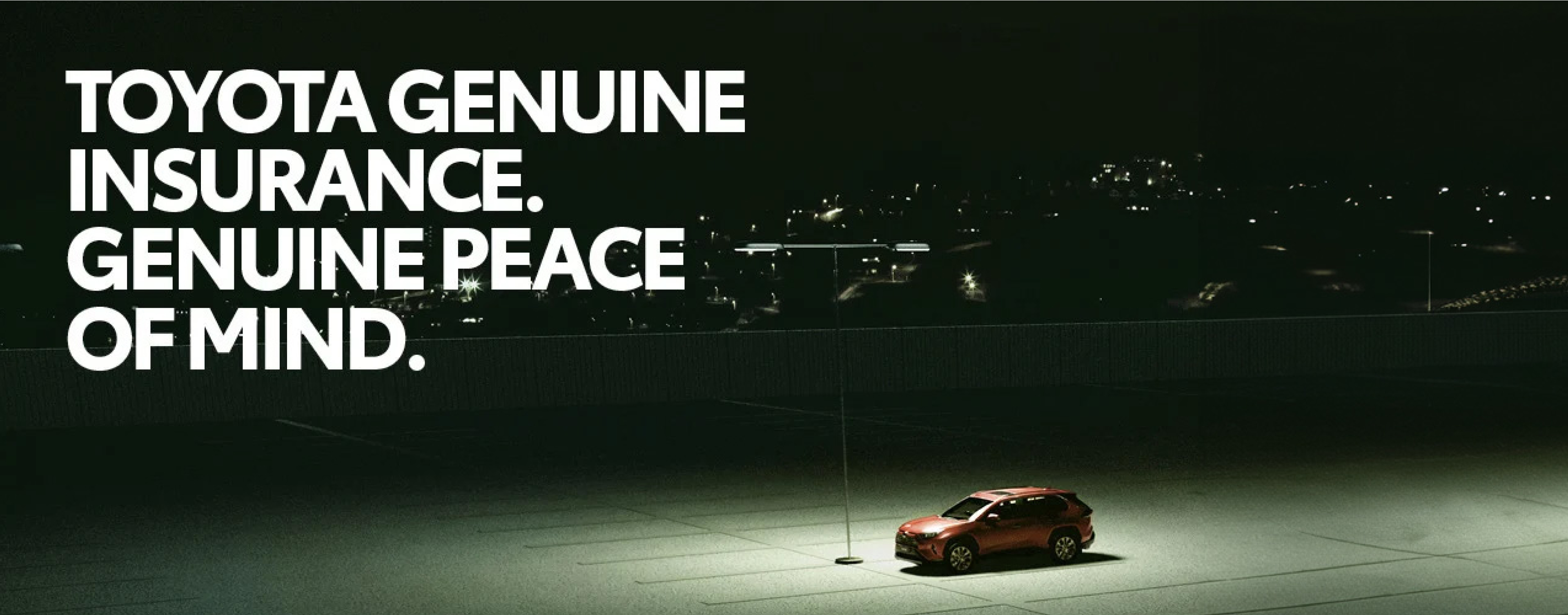 A red Toyota hatchback stands parked alone in a parking lot at night, illuminated by parking lot lighting, a night cityscape in the distance. ‘TOYOTA GENUINE INSURANCE. GENUINE PEACE OF MIND.’ is superimposed onto the image.