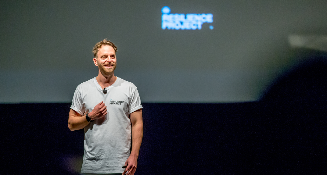 Hugh van Cuylenburg of The Resilience Project on stage speaking to an audience at a conference.