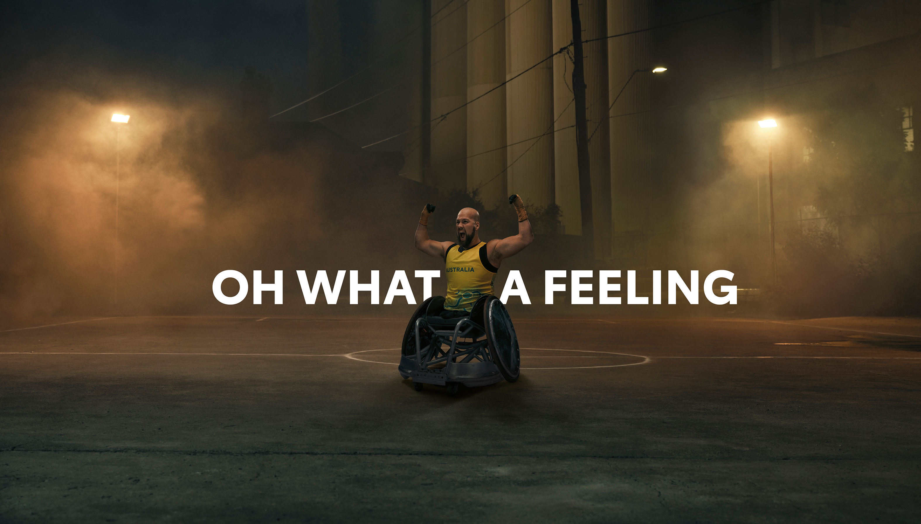 Australian Paralympian wheelchair rugby player Ryley Batt, posing on moodily lit, foggy basketball court at night, with the superimposed title of what a feeling.
