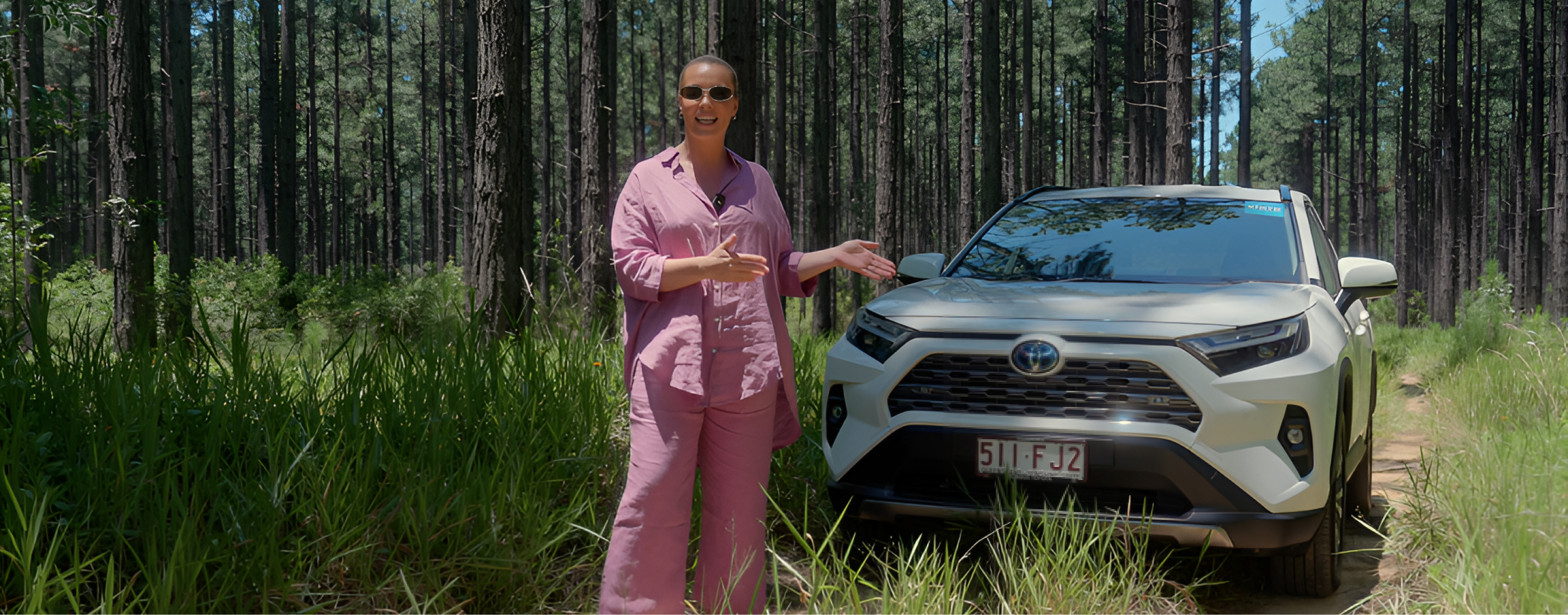Former AFLW superstar Abbey Holmes stands in front of her white Toyota RAV4 on her weekend away, in a forest on the Sunshine Coast.