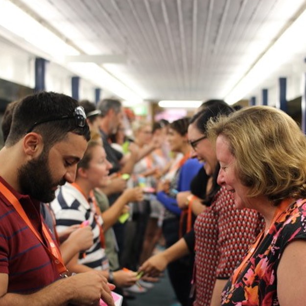 A long, well-lit hall of people lined up down the hall in two rows facing each other, participating in an icebreaker exercise to get to know each other.