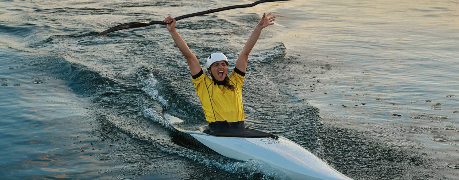 Australian Olympian canoeist Jess Fox, canoeing, raising her hands and paddle in the air in celebration.