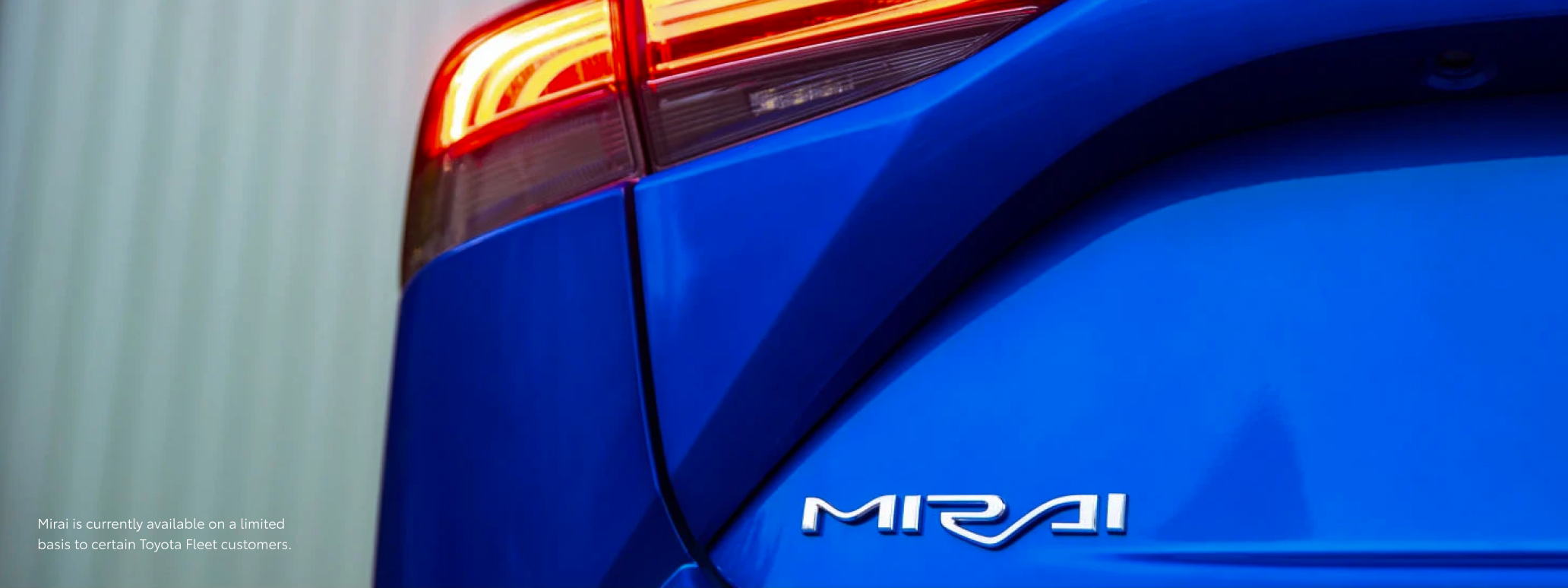 The silver ‘MIRAI’ badge sitting underneath the glowing left taillight of a Toyota Mirai.