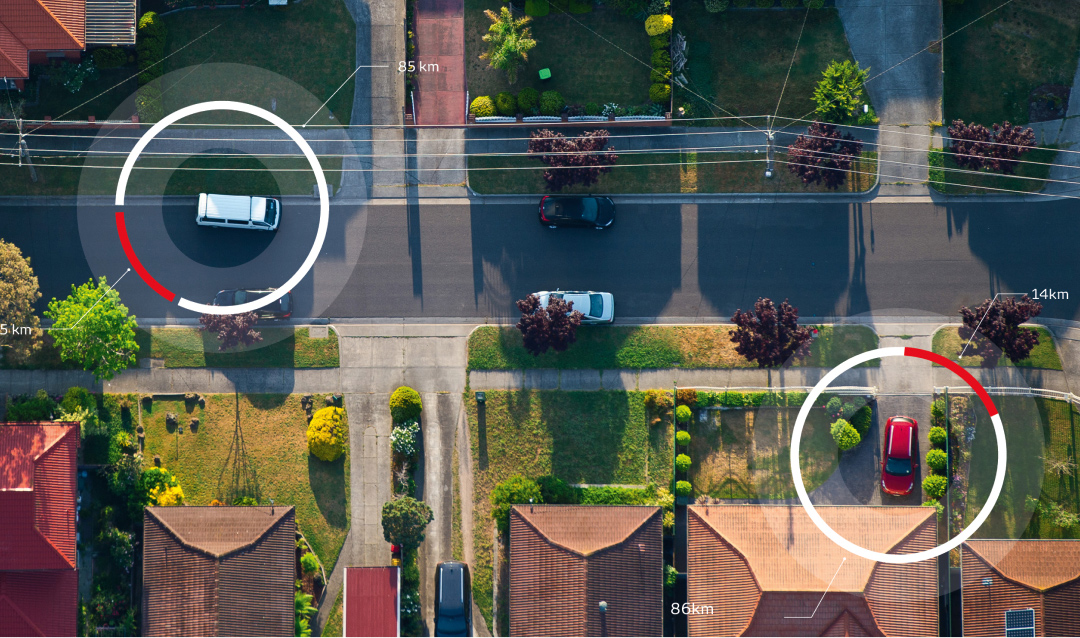 A birds eye view of a suburban street on a sunny afternoon, two Toyota vehicles highlighted by red and white circles.