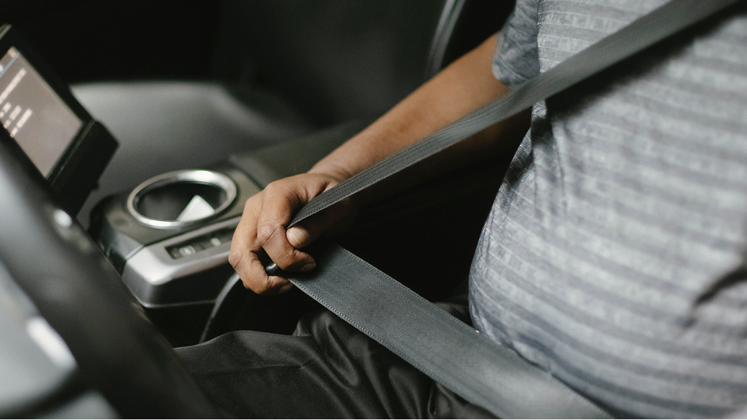 A man doing up his seatbelt in a Toyota vehicle.