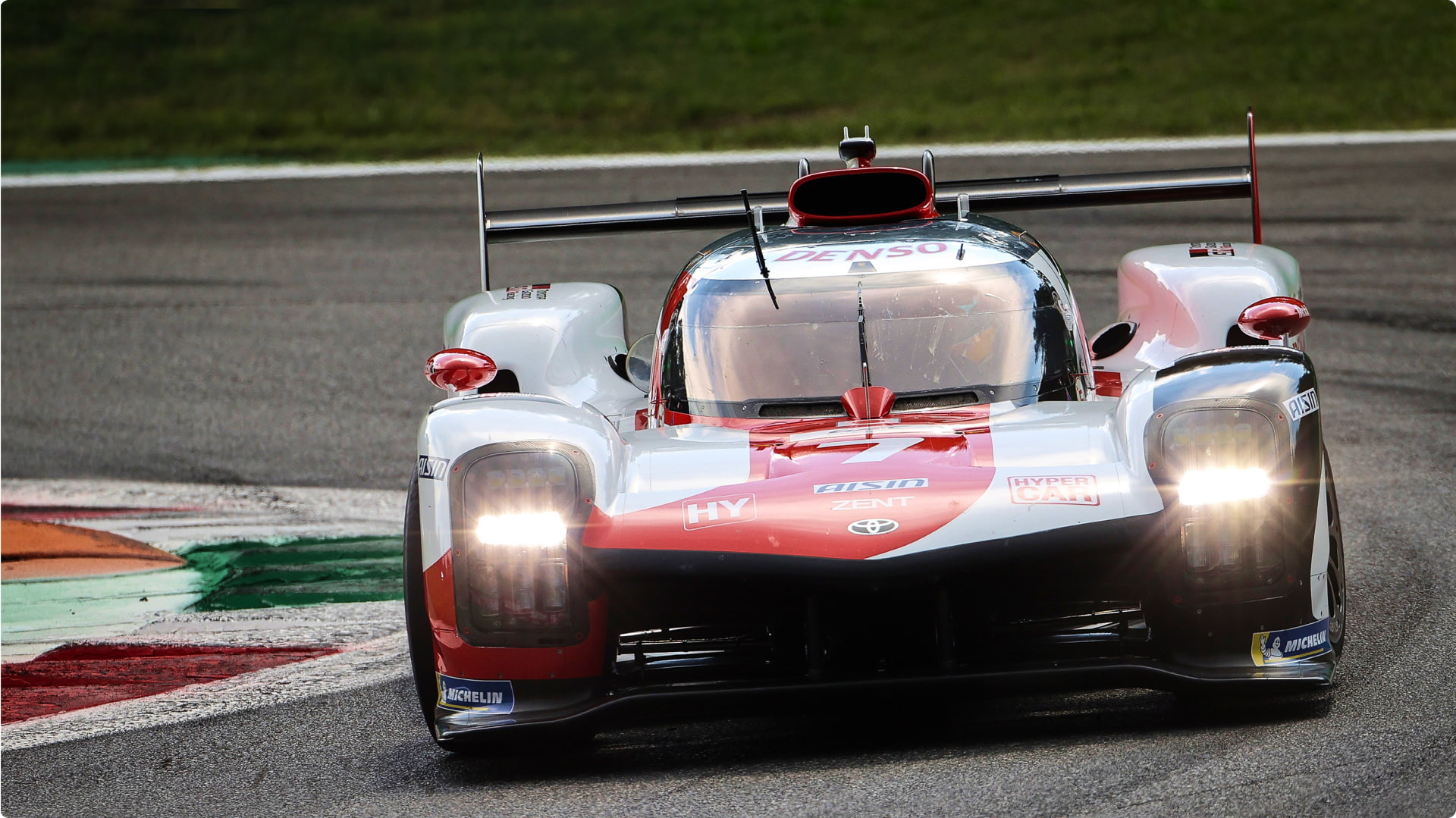 A 2021 W E C G R 010 Hybrid racecar on the wet track at the 2021 '24 Hours of Le Mans', cornering a bend.