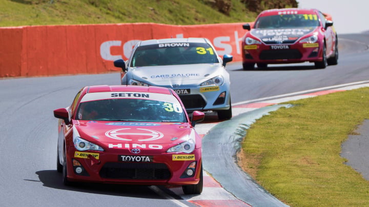 Three Toyota G R 86s in racing livery competing on a sunny day at Gold Coast 500.
