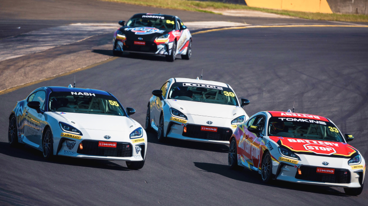 Four Toyota G R 86s in racing livery competing at the Townsville 500, the track scrawled with wheel marks.