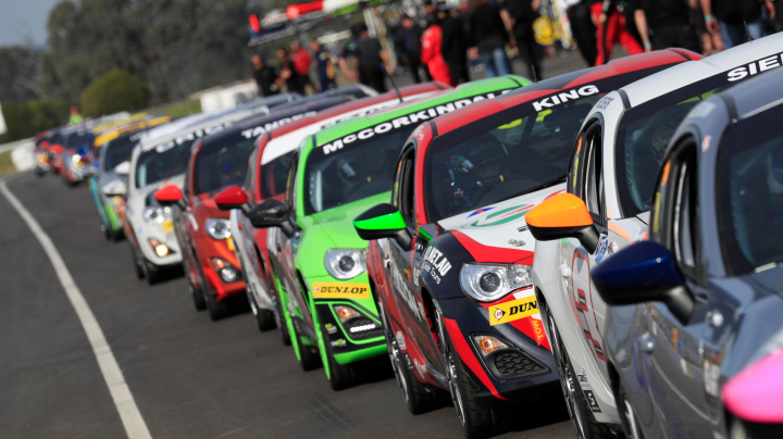 A convoy of Toyota G R 86s in racing livery, travelling in a neat line past onlookers at the Winton Supersprint.
