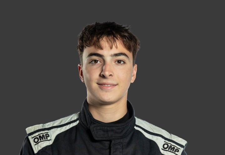 A headshot of professional T G R A driver Salvatore Imbrogno in a black and white racing suit against a grey background.
