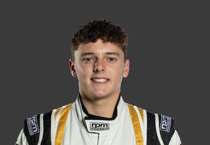 A headshot of professional T G R A driver Jett Murray in a white, black and gold racing suit against a grey background.