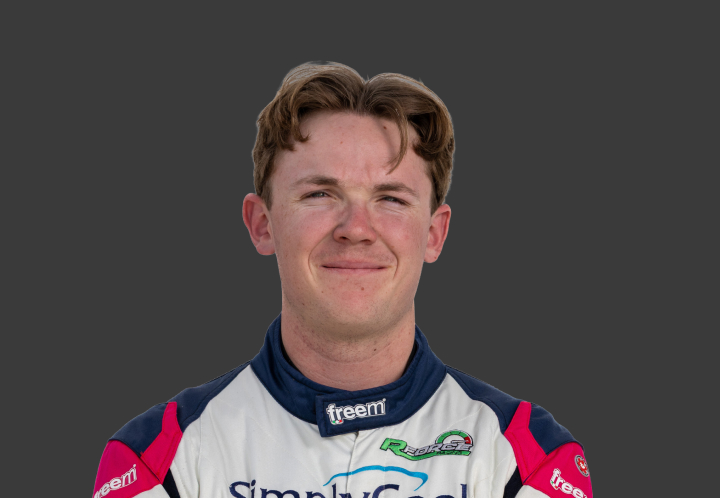 A headshot of professional T G R A driver Zane Rinaldi in a white, navy blue and red racing suit against a grey background.