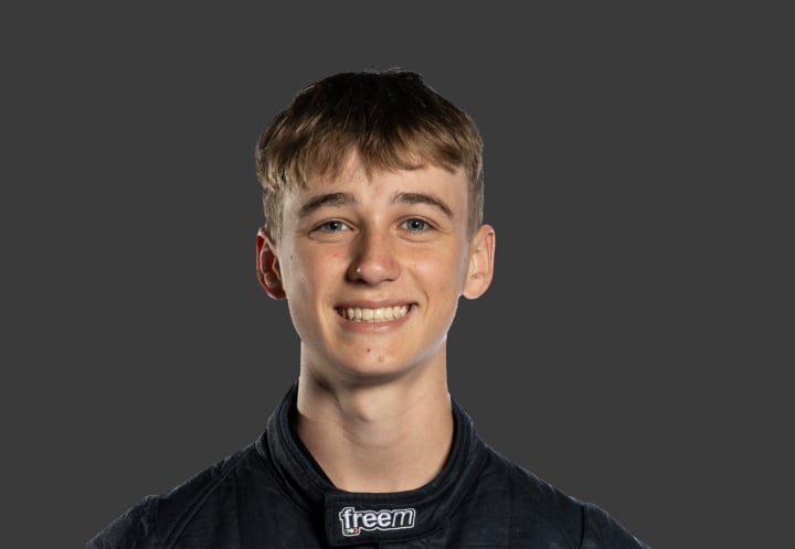 A headshot of professional T G R A driver Jack Szewczuk in a black racing suit against a grey background.