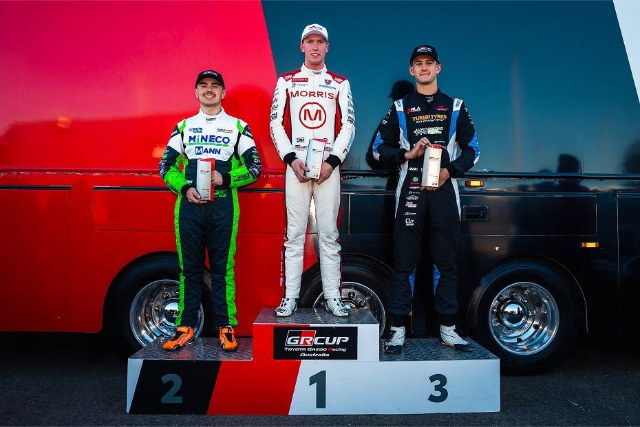 Professional racing drivers on a T G R A Cup podium. First place (middle) is Max Geoghegan, second Place (left) is Bradi Owen, third place is James Lodge.
