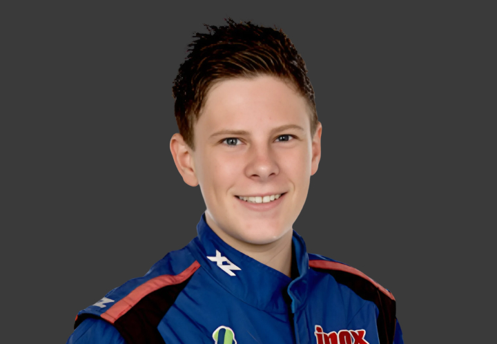 A headshot of professional T G R A driver Declan Fraser in a blue, black and orange racing suit on a grey background.