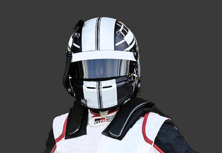 A headshot of a professional T G R A driver in a closed helmet with the visor down, on a grey background.