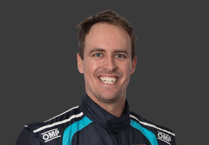 A headshot of professional T G R A driver Tim Brook on a grey background.