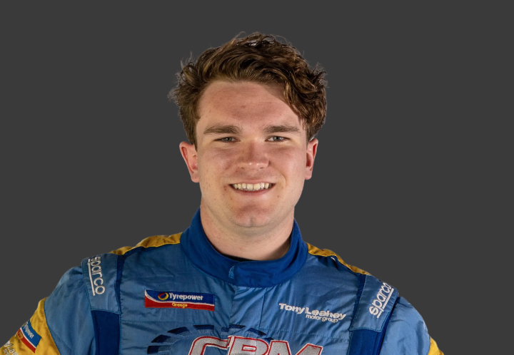 A headshot of professional T G R A driver Cody Burcher in a blue and orange racing suit on a grey background.