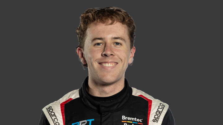A headshot of professional TGRA driver Clay Richards in a black, white and red racing suit against a grey background.