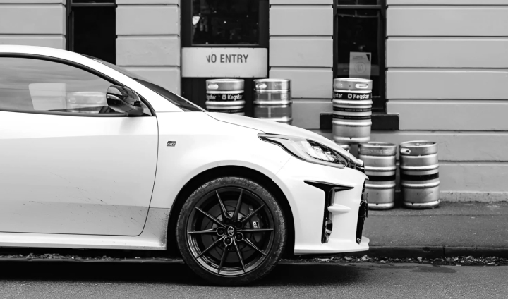 A Glacier White Toyota G R Yaris parked in front of The Rose Hotel, Fitzroy, with beer kegs stacked on the footpath against the beige facade.