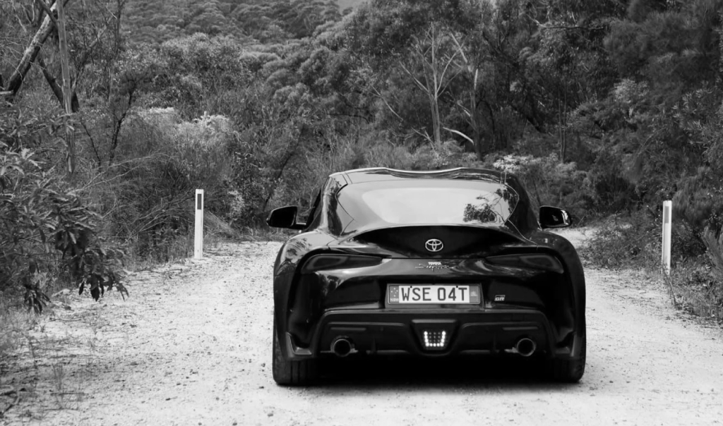 A G R Supra in Bathurst Black, driving down an unsealed road in the bush towards the Blue Mountains.