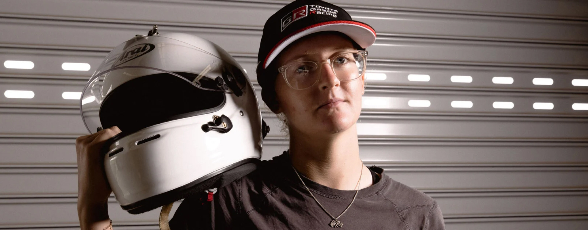 Professional racing driver Holly Espray posing confidently with a racing helmet resting on her right shoulder, wearing a TOYOTA GAZOO Racing Australia baseball cap.