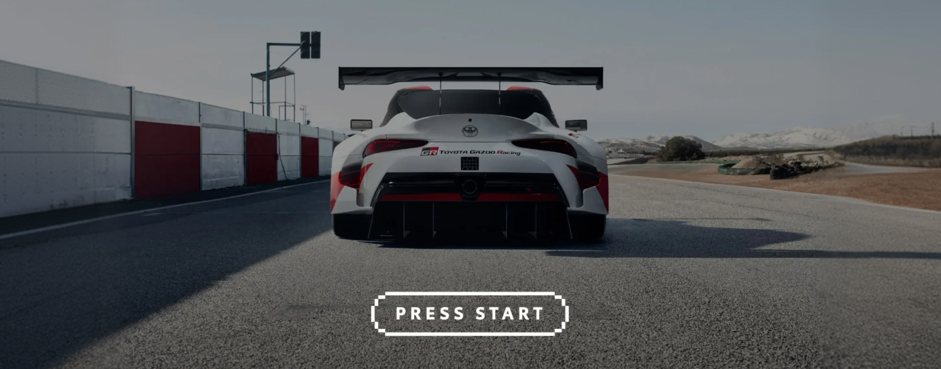 A video-game render, the rear of a Glacier White G R Supra with a large racing spoiler and red and black  TG R A decals. "Press start" is superimposed below.