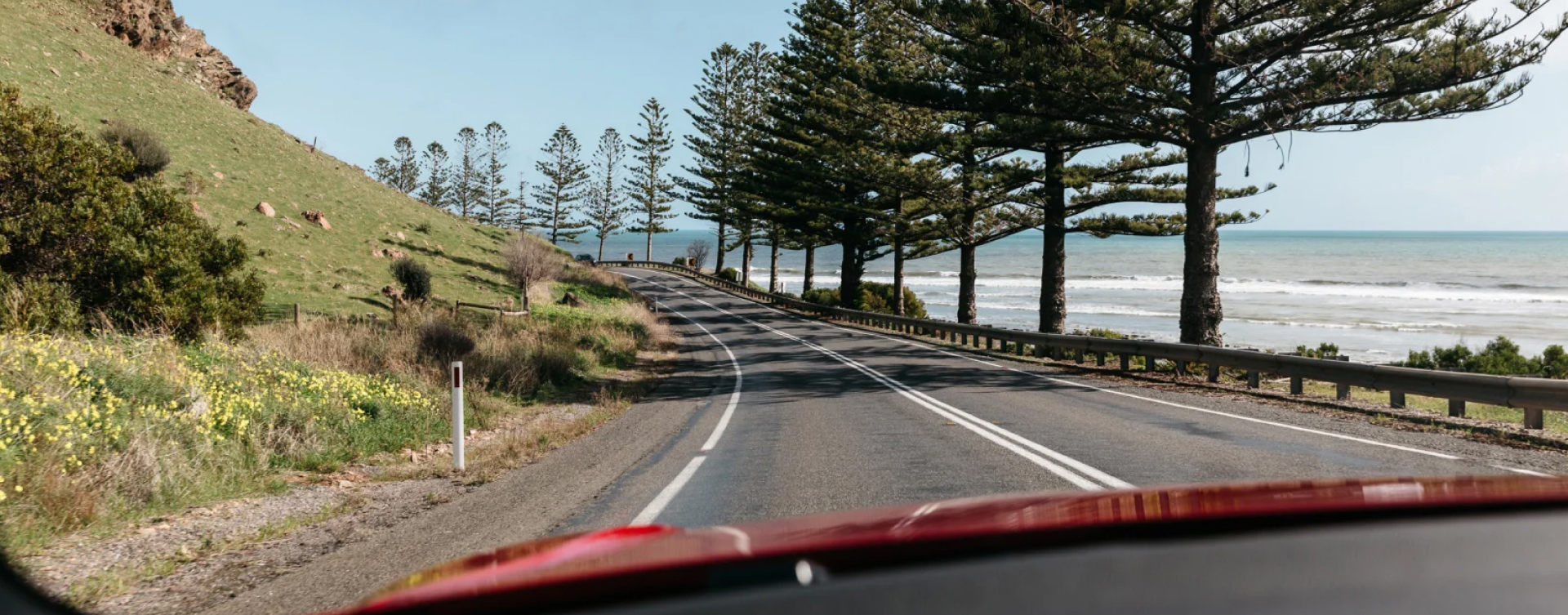 A view from the dashboard of a Monza Red G R Supra, of the winding road along the Fleurieu Peninsula in South Australia.