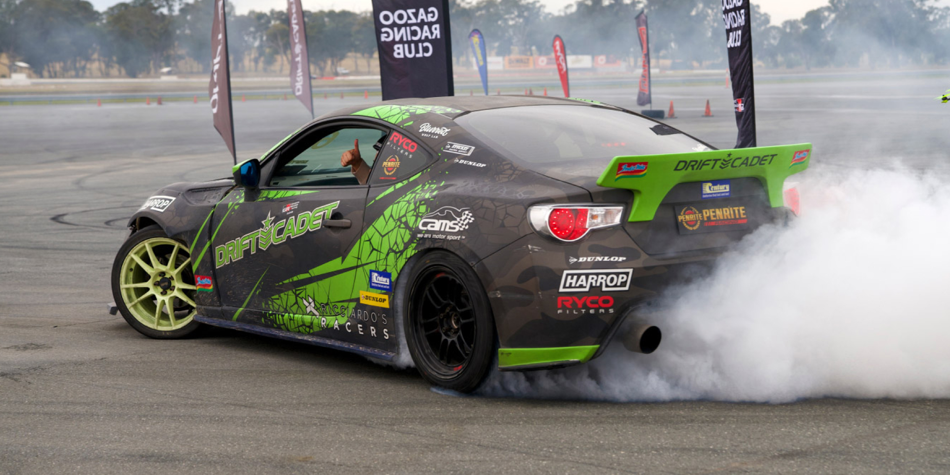 Peter does a burnout on the skidpan, in a supercharged GR86 with black and green decals.