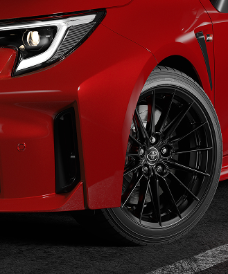 A cropped look at the headlight and front fender vent on a Toyota G R Corolla in Feverish Red.