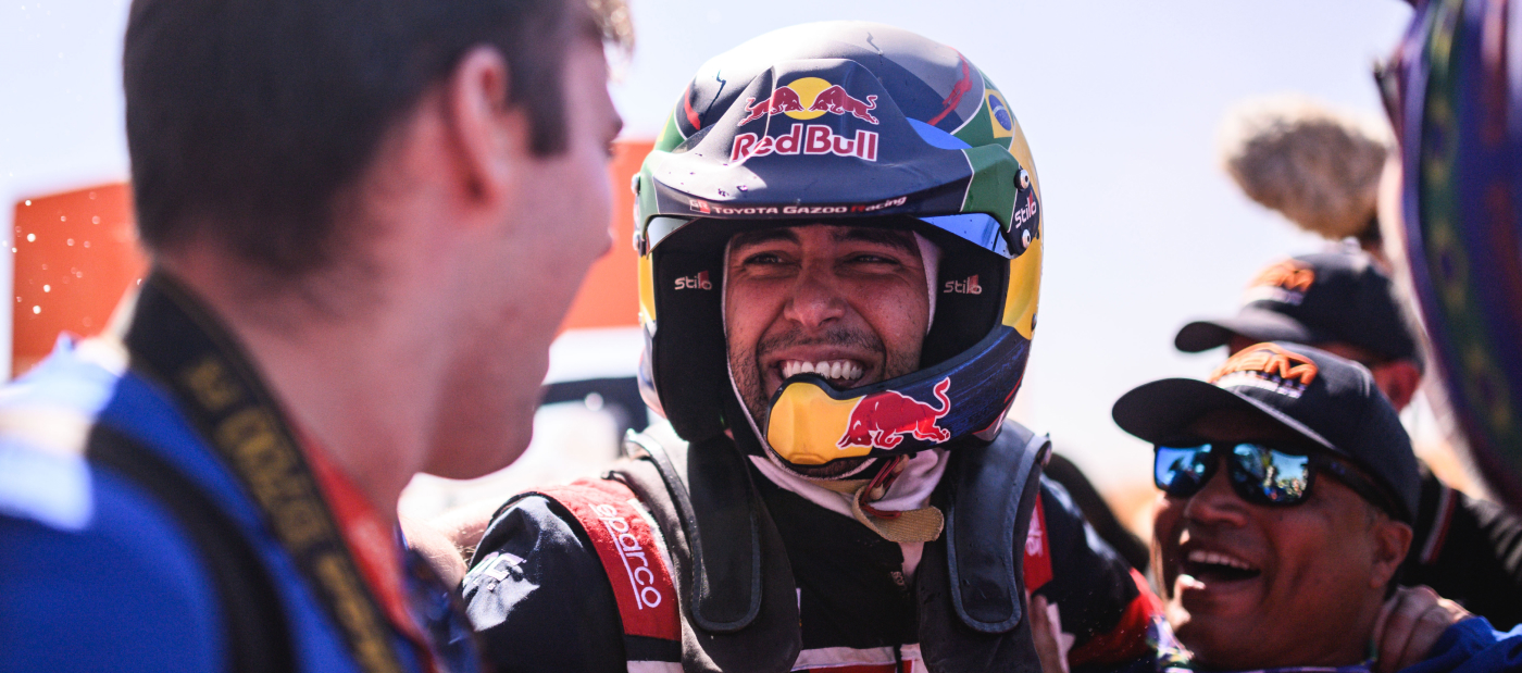 Professional Toyota Gazoo Racing driver Lucas Moraes in racing suit, smiling and celebrating with his team after a win.