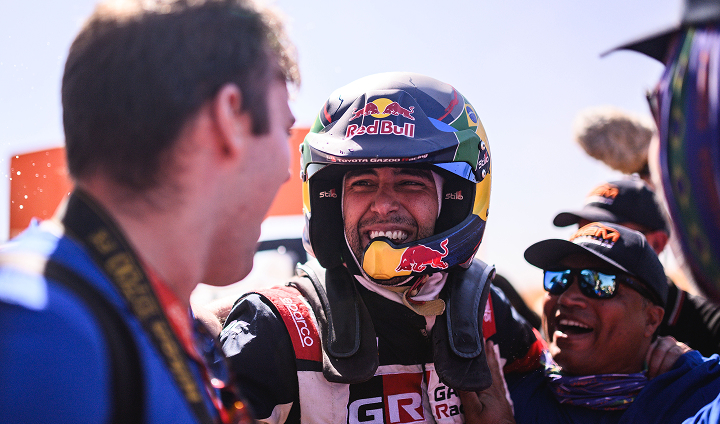 Professional Toyota Gazoo Racing driver Lucas Moraes in racing suit, smiling and celebrating with his team after a win.