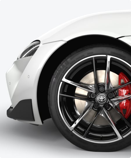 Front wheel of a white GR Supra, with silver alloys and red brake caliper.
