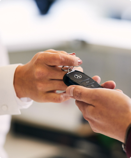 The hands of a Toyota Dealer passing keys to a customer.