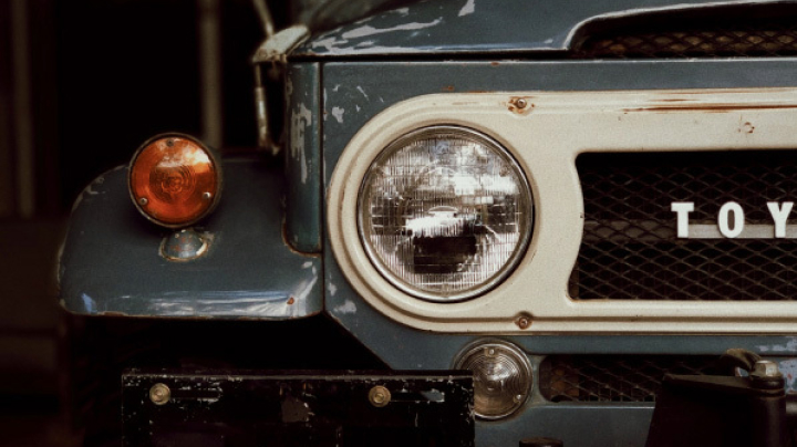 The close-up of a worn and tattered LandCruiser headlight.