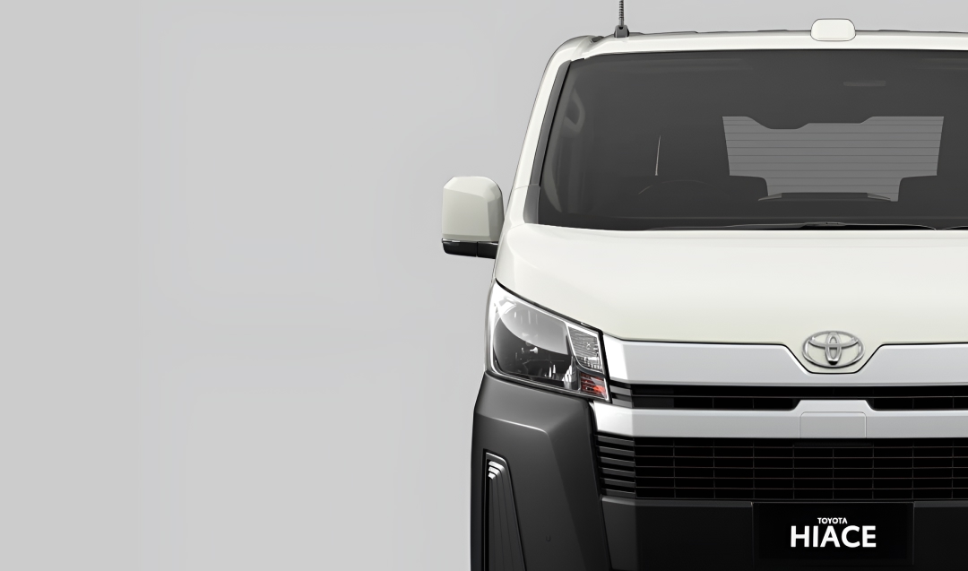 A front-facing grey white Toyota HiAce.