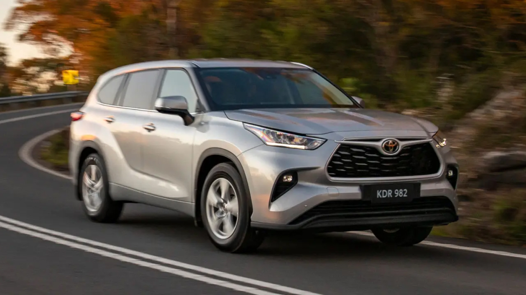 A silver Toyota Kluger driving around the bend of a road.