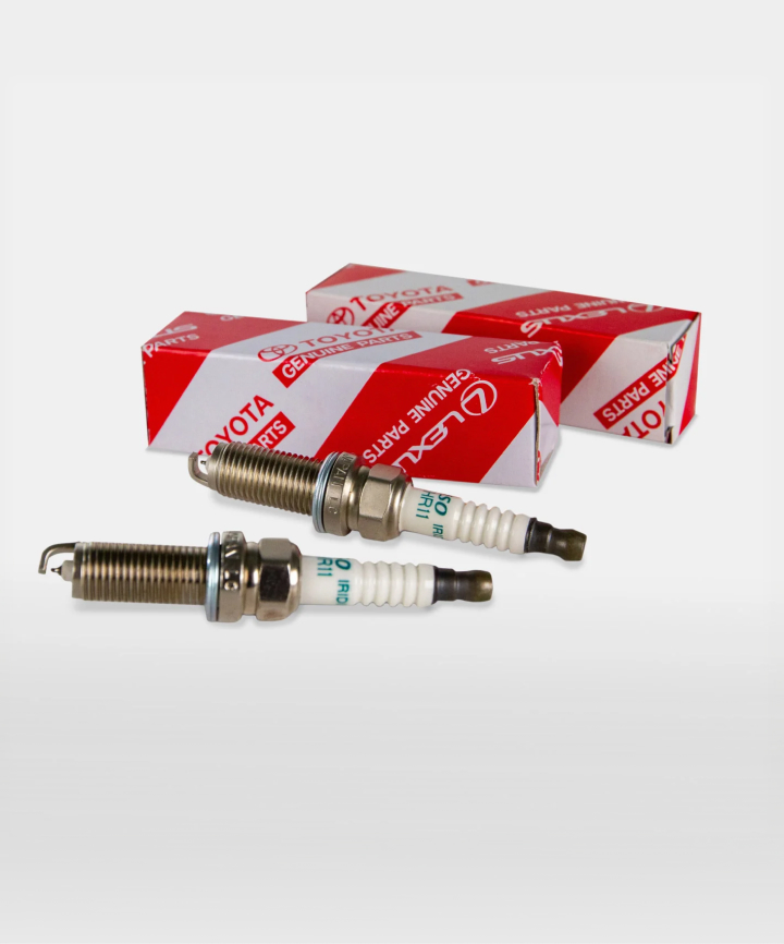 Two spark plugs next to their red and white Toyota packaging.
