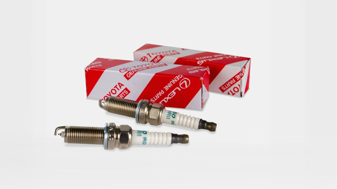 Two spark plugs next to their red and white Toyota packaging.