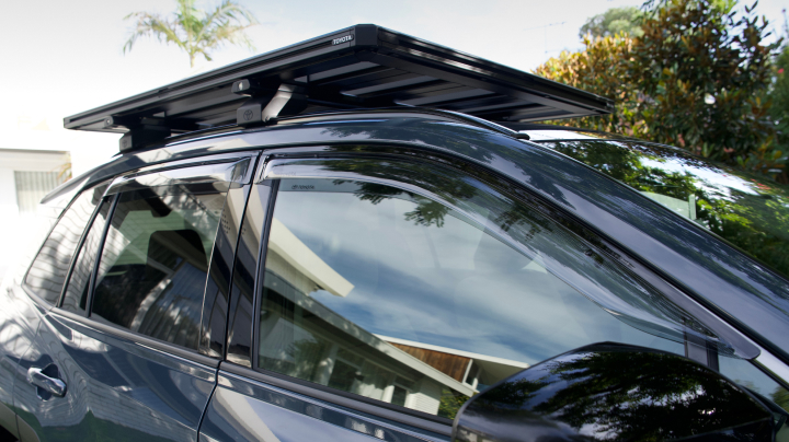 A dark grey Toyota with flat roof platform and tinted weather shields fitted over the side windows.