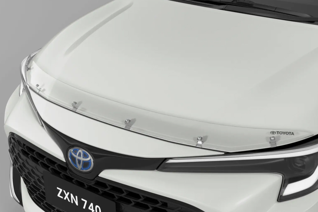 The front of a G R Corolla in Glacier White, fitted with a Toyota Genuine Bonnet Protector.