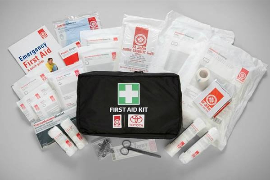 A Toyota Genuine First Aid Kid, with the contents of the kit laid out around the first aid bag that the kit comes in.