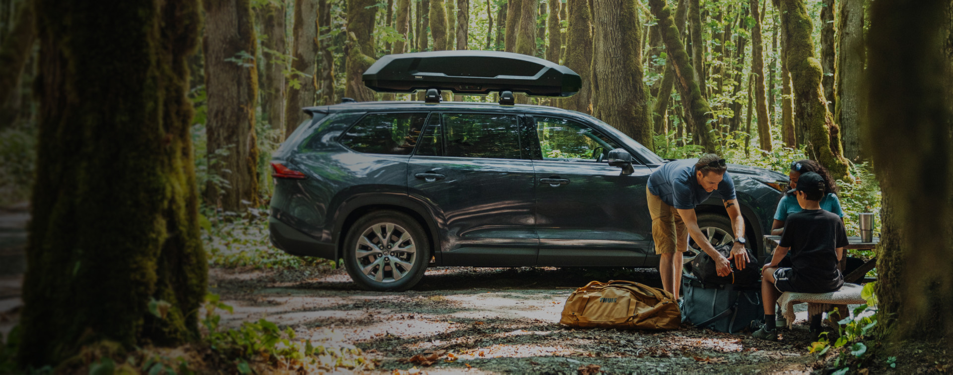 Toyota SUV equipped with Genuine Roof Racks parked at a forest campsite with a family.