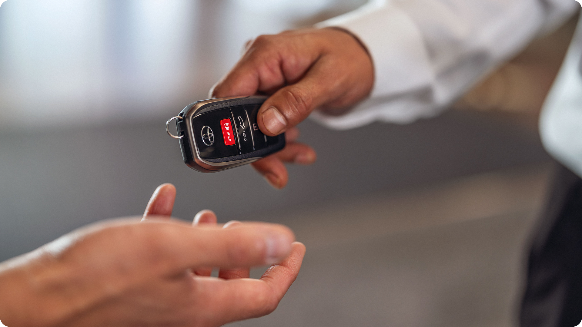 Person handing over a Toyota smart key fob