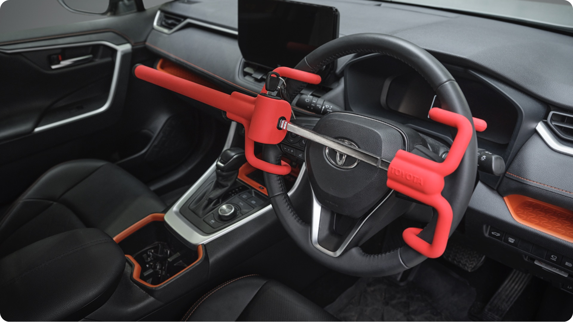 Red anti-theft steering wheel lock attached to a Toyota steering wheel.
