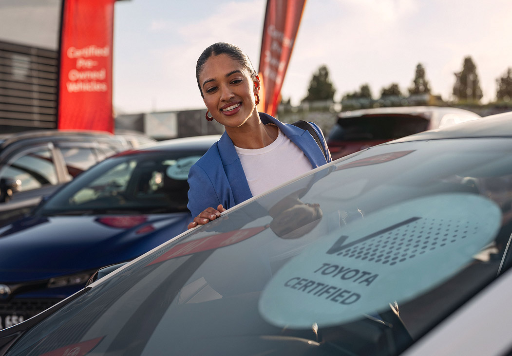 A lady handing something to a lady inside a car